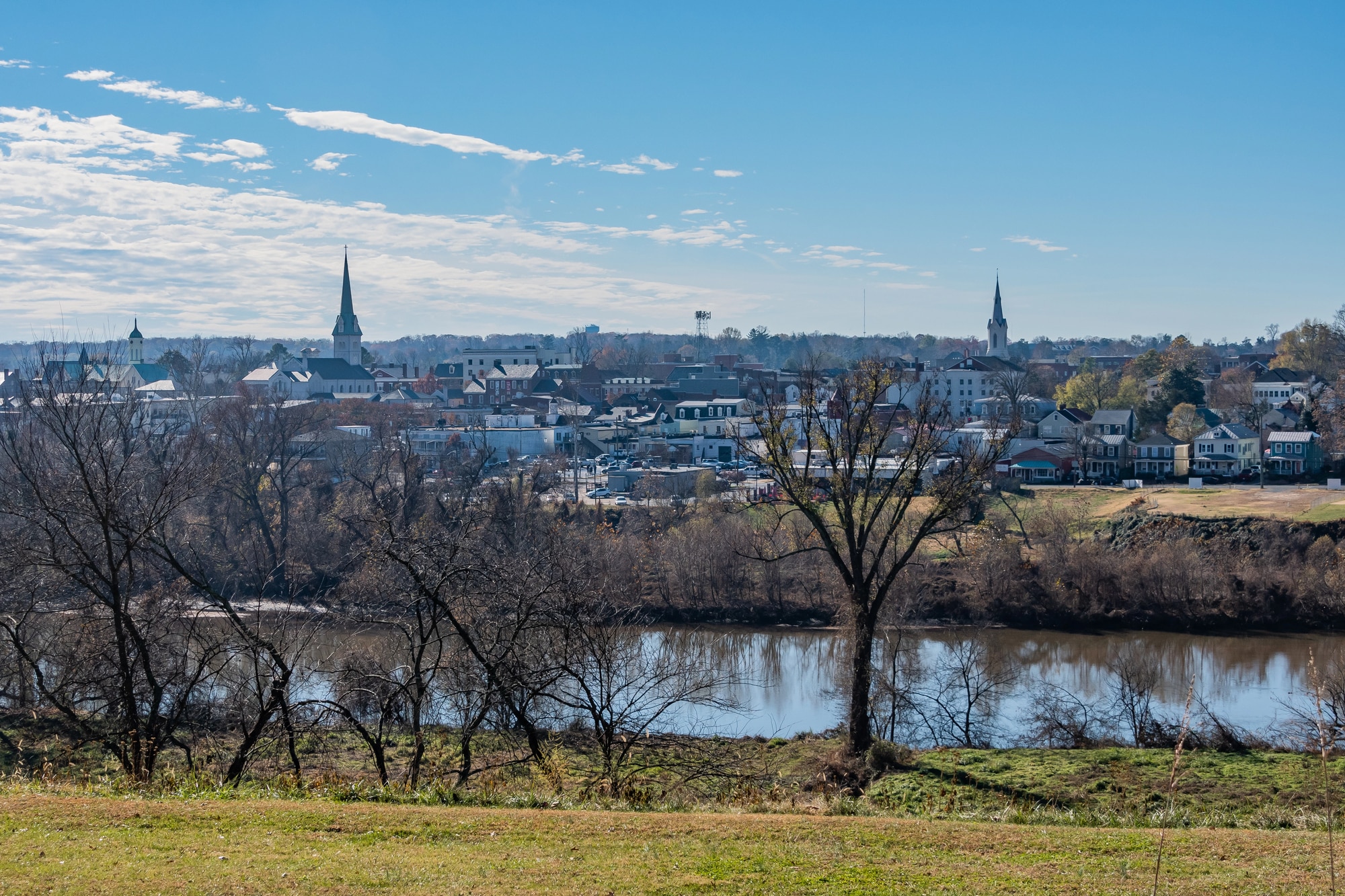 View of The City of Fredericksburg across the Rappahannock River with church steeples under a blue sky