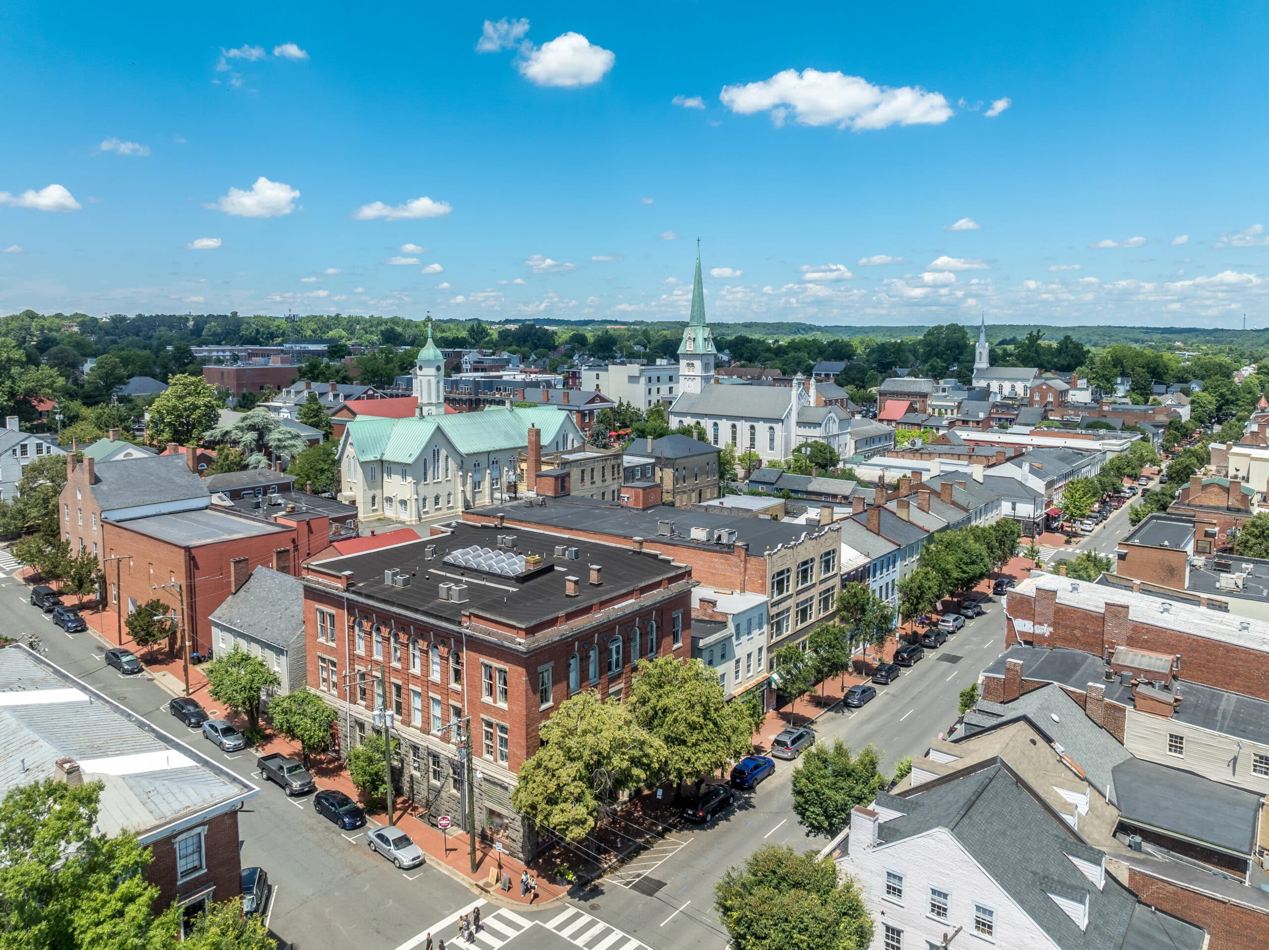 Aerial view of a historic downtown Fredericksburg with church steeples under a bright blue sky